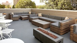 An outdoor seating area with wicker sofas, white tables, and a fire feature. - Holiday Inn Louisville Downtown (Louisville)