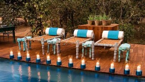 Zona junto a la piscina con sillones de descanso y velas.
