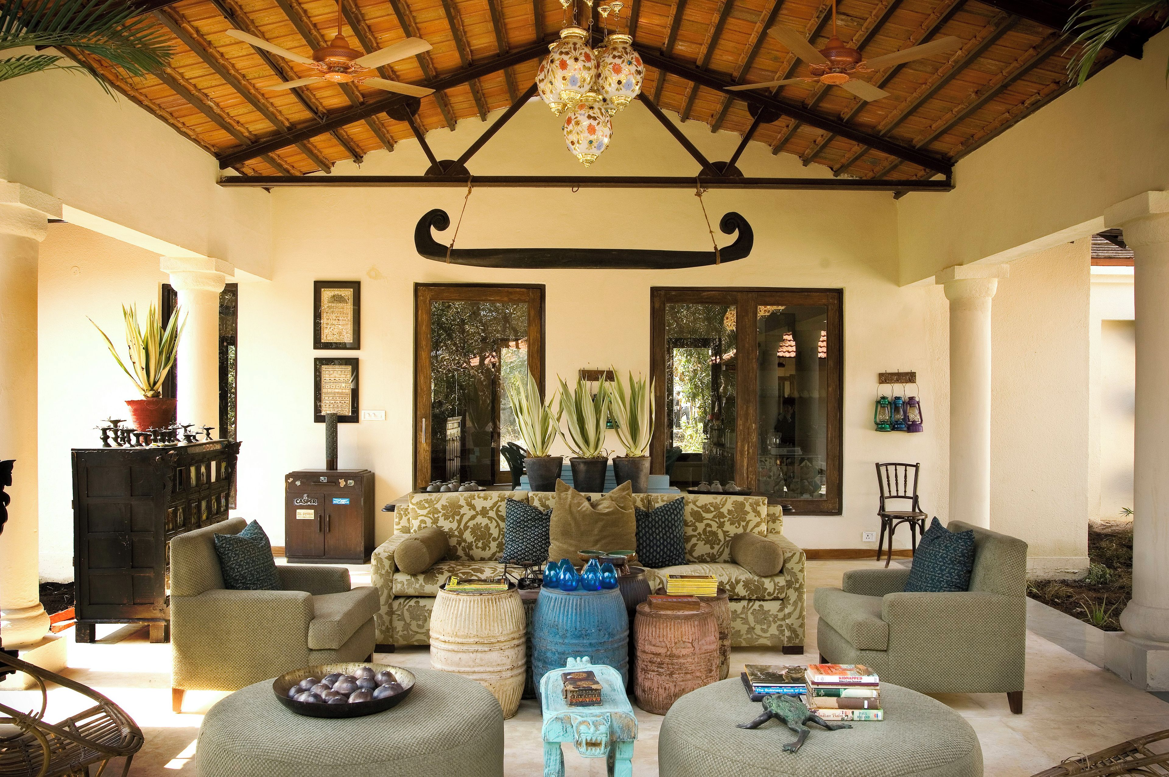 A spacious living area with a high ceiling, a sofa set, a fireplace, and a large window.