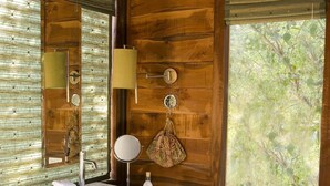 A wooden cabin bathroom with a sink, mirror, and window. - Baghvan A Taj Safari Pench National Park (Kurai)