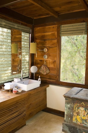 Ein Badezimmer einer Holzhütte mit Waschbecken, Spiegel und Fenster.
