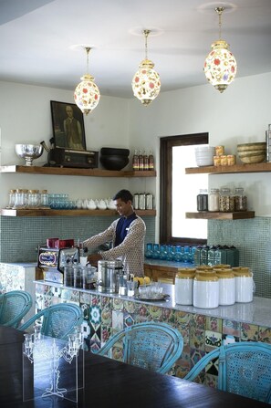 Una cocina con una persona preparando comida, un salpicadero de azulejos y diversos utensilios y recipientes de cocina.