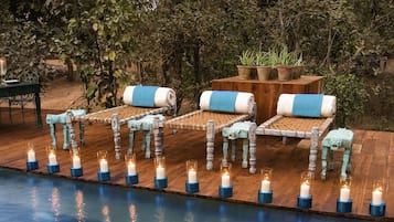 A poolside area with lounge chairs and candles.