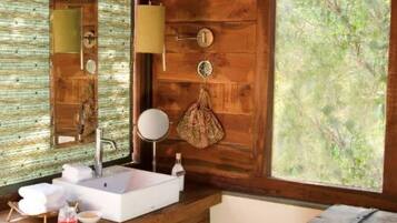 A bathroom with a wooden wall, a large window, a sink, a mirror, and a towel rack.