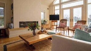 Un salón amplio con una mesa de centro de madera, un televisor de pantalla plana y asientos cómodos.