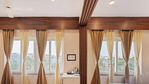 A hotel room with a bed, a desk, and curtains. - Treebo The Aura (Bhubaneshwar)