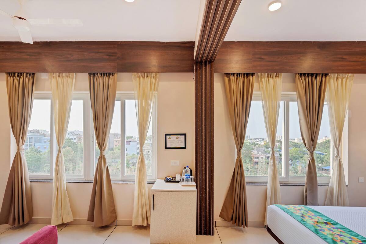 Una habitación de hotel con una cama, un escritorio y cortinas.