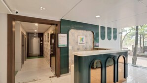 A reception area with a modern design, including a reception desk, a signboard, and a glass door leading to a hallway. - Treebo The Aura (Bhubaneshwar)