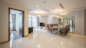 A spacious living room with a dining area, a television, and a large window. - Landmark Condotel Art By KaySuite  (Ho Chi Minh City)
