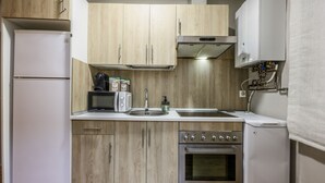 Une cuisine compacte dotée de meubles en bois, d’un four à micro-ondes encastré, d’un grille-pain, d’un évier, d’une cuisinière et d’un lave-vaisselle.