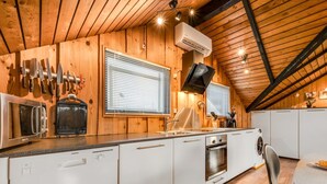 A modern kitchen with wooden walls, a microwave, a toaster, and a sink.