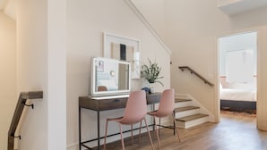 A modern room with a desk, two pink chairs, a mirror, and a staircase leading to another room. - The Conway | Ensemble Escape in DT Nash | 5 Bdrs (Nashville)