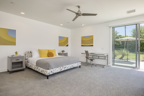 A modern bedroom with a bed, desk, and large sliding glass door to a balcony.