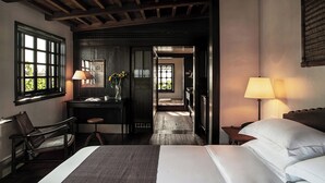 A hotel room with a bed, a desk with a lamp, a chair, and a view of the outside through a window. - Dali Ancient Town Anyu Hotel (Dali)