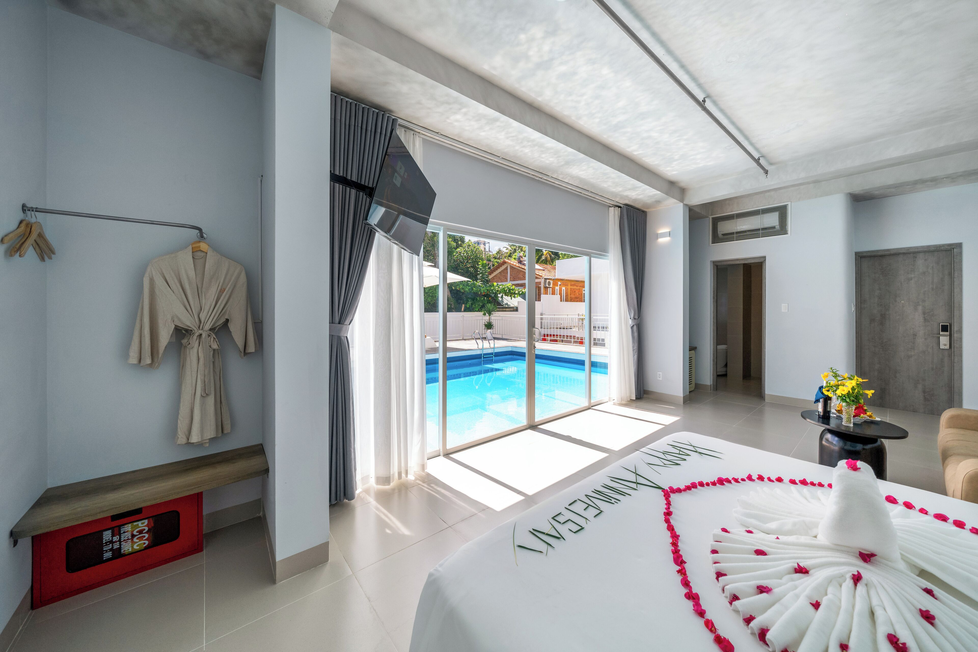 A hotel room with a large bed, a view of a swimming pool, and a sliding glass door.