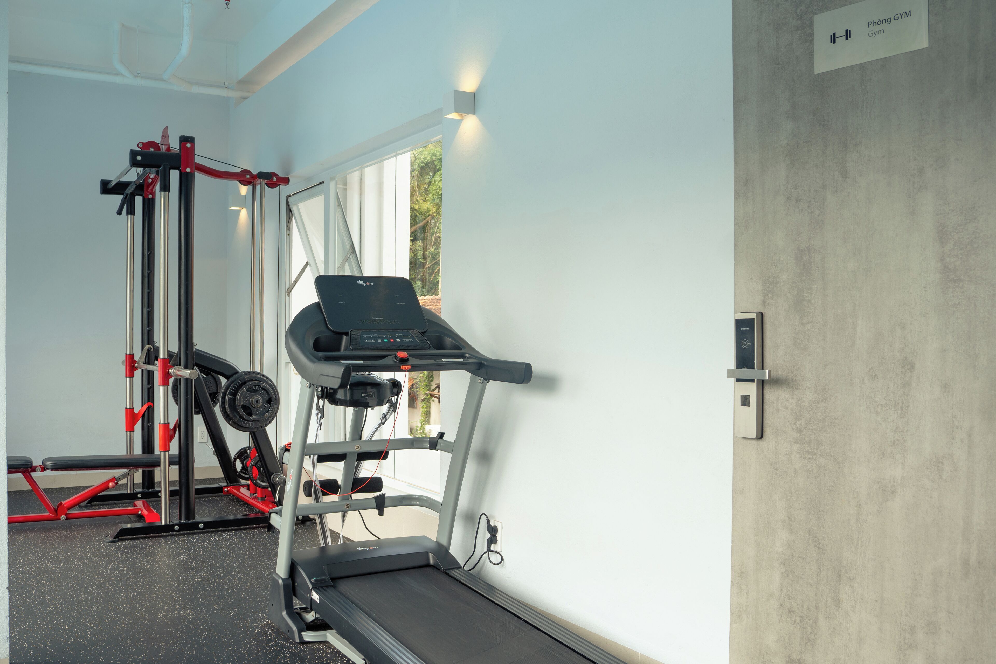 A gym with a treadmill, weight machine, and a bench.