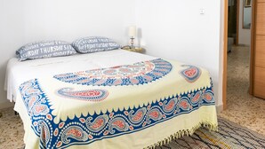 A bed with a patterned bedspread, a bedside lamp, and a patterned rug on the floor. - Holiday Home in Cadiz by the Sea (Cadiz)