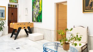 A room with a foosball table, a sofa, a chair, and a table with a plant. - Holiday Home in Cadiz by the Sea (Cadiz)