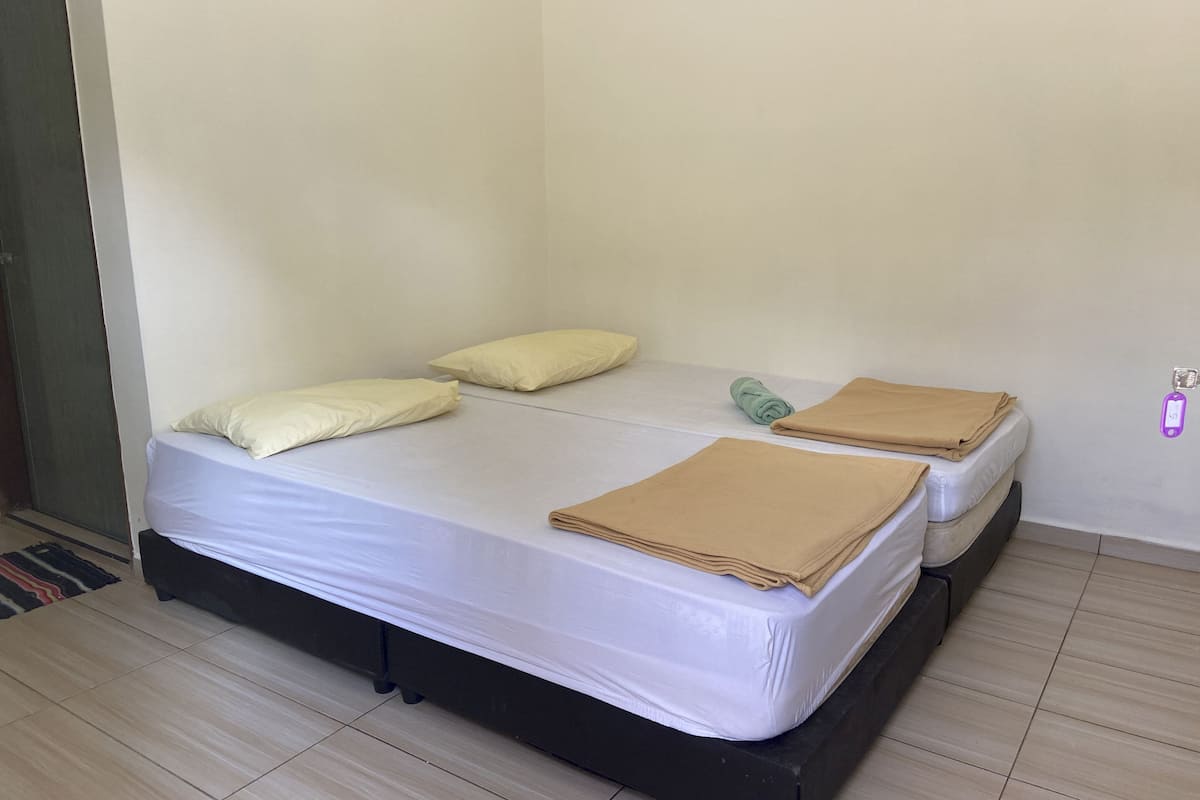 A single bed with a white mattress, two pillows, and a folded blanket.