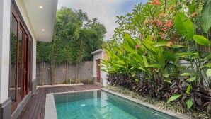 Una piscina rectangular con agua cristalina, rodeada por una terraza de madera y abundante vegetación.