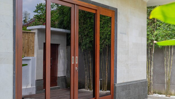Un edificio moderno con grandes puertas de vidrio y una terraza de madera.