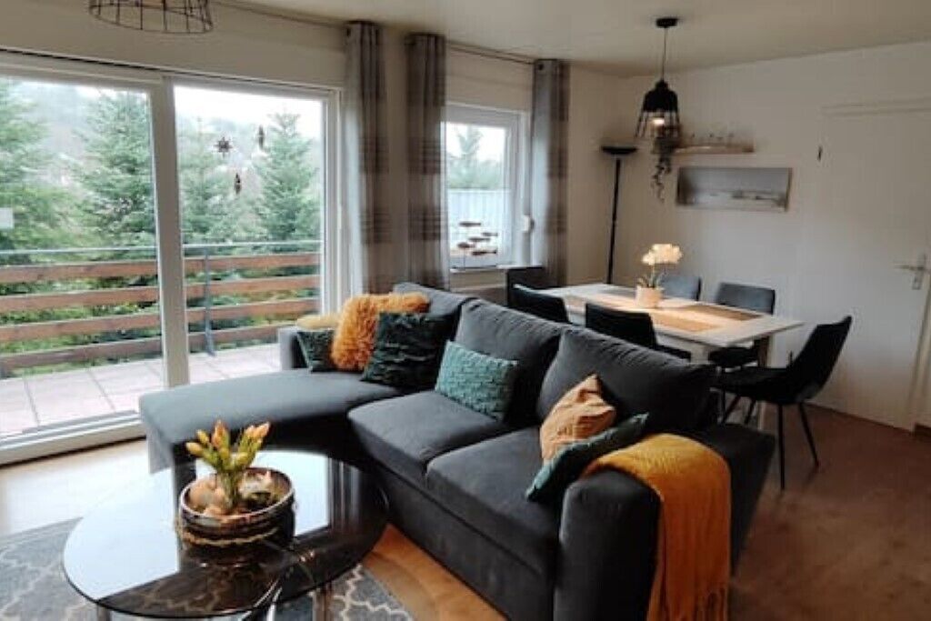 A modern living room with a dark grey sofa, a round coffee table, and a dining area with a white table and black chairs.