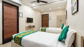 A hotel room with two beds, a ceiling fan, an air conditioner, a television, and a wardrobe.