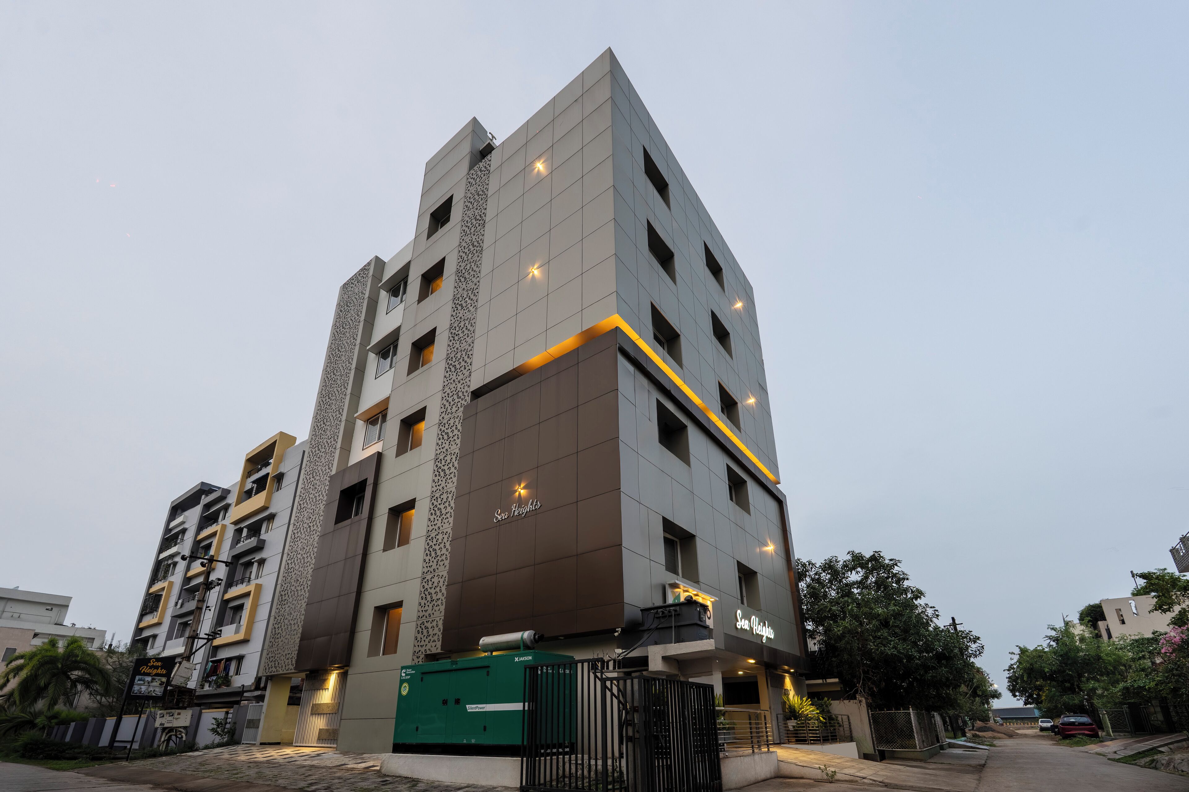 A modern multi-story hotel with a prominent entrance, a gated driveway, and a well-lit facade.