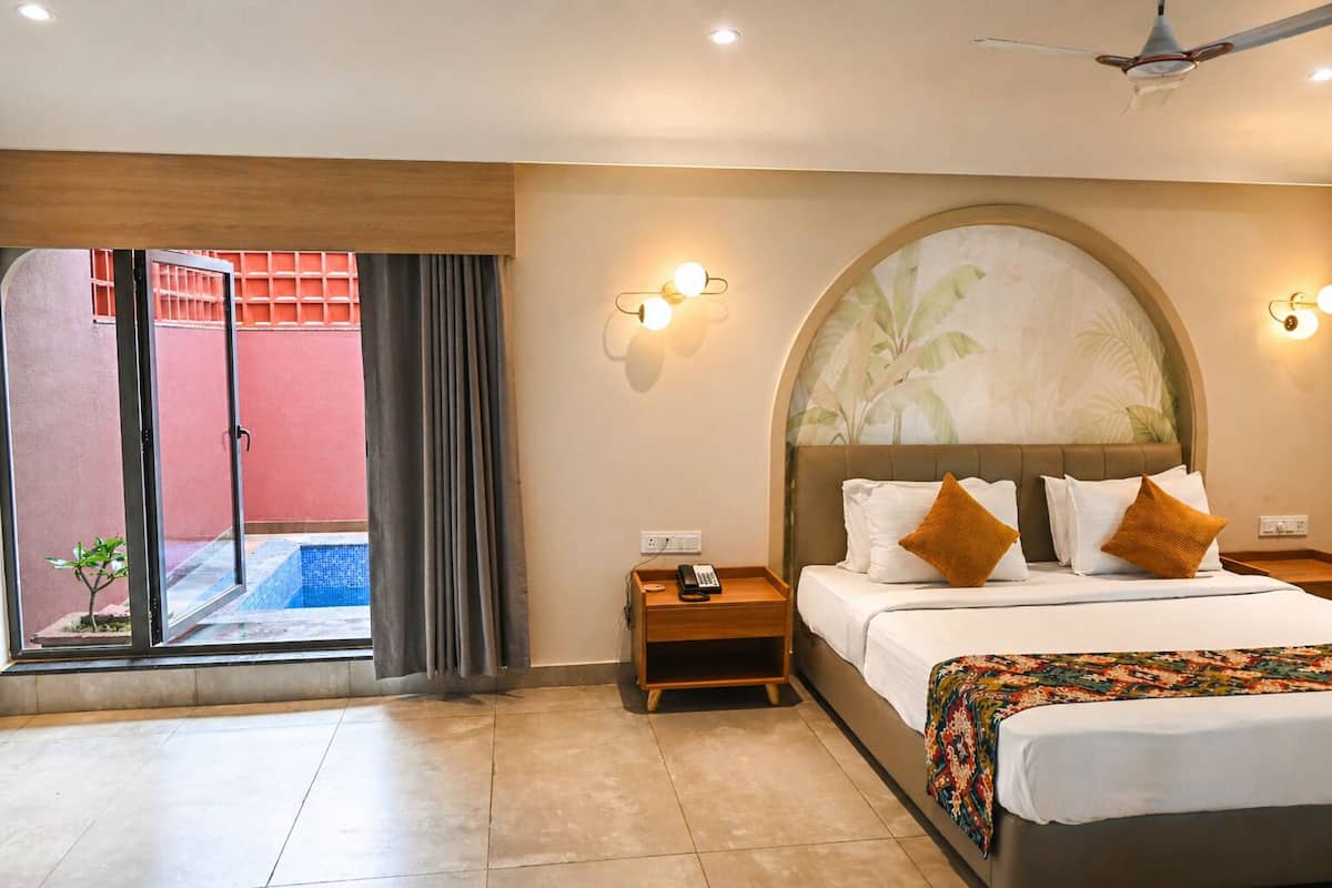 A hotel room with a bed, bedside tables, a telephone, a ceiling fan, and a view of a swimming pool through a glass door.