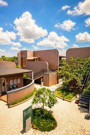 Un edificio moderno con paredes curvas, una escalera y un pequeño jardín.