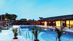 A pool area with lounge chairs, a pool, and a building with arched doorways.