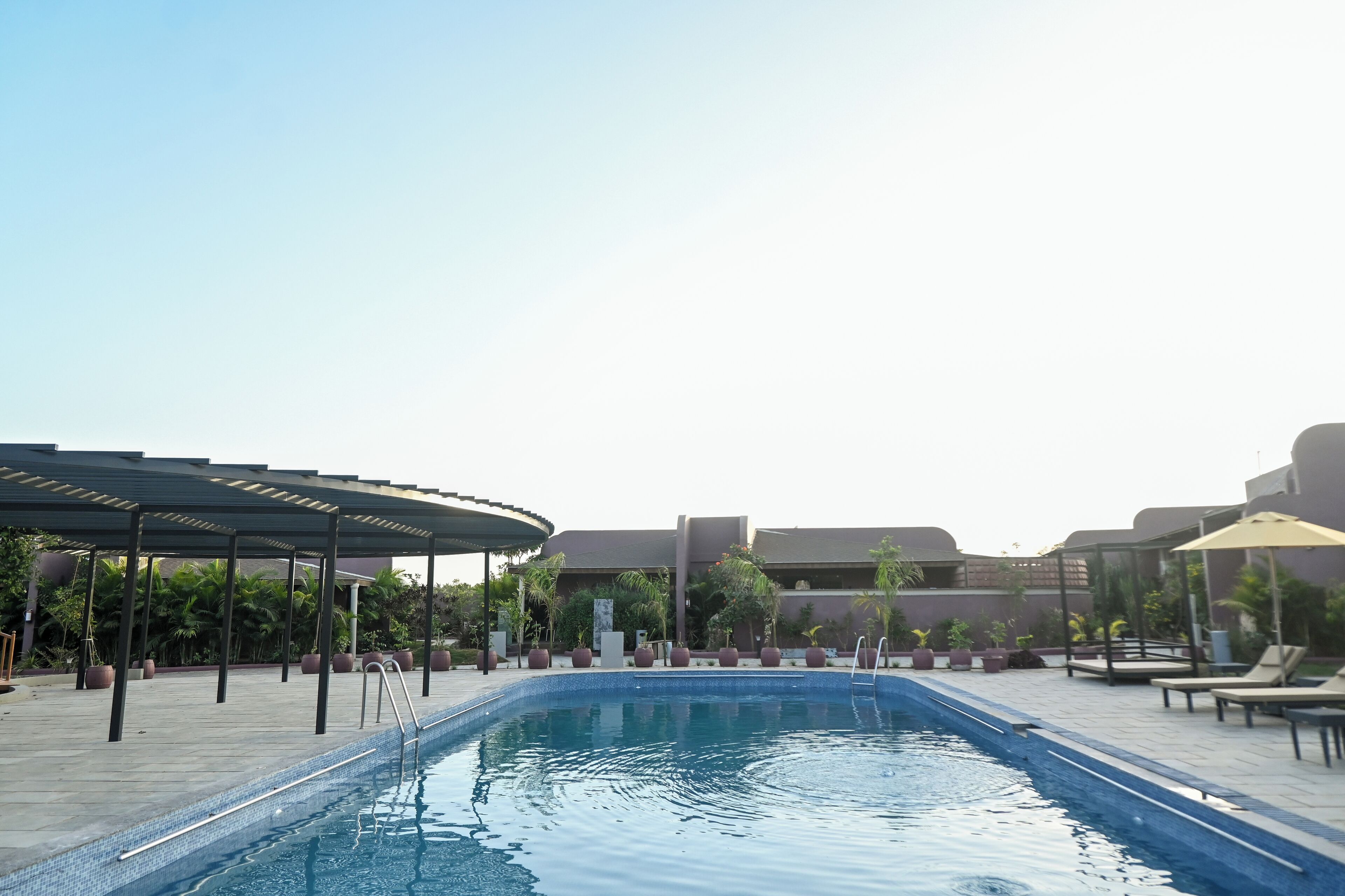 Una piscina al aire libre, sombrillas, sillones reclinables de piscina