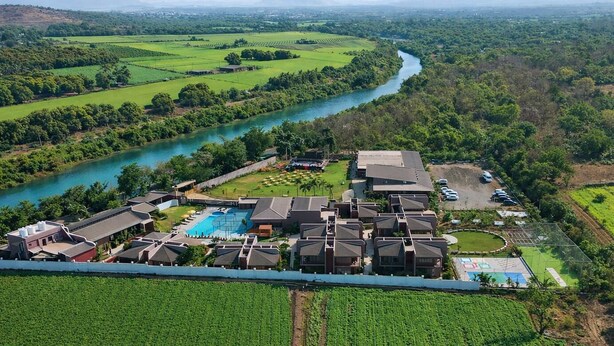 An aerial view of a resort with multiple buildings, a swimming pool, and a river.
