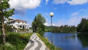 A paved pathway beside a body of water, a white building with a red roof, and a street lamp.