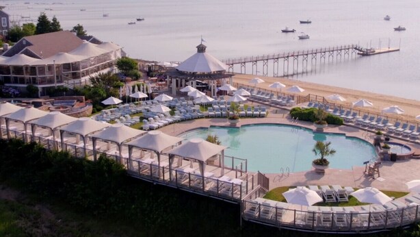 Un complexe hôtelier doté d’une grande piscine, de chaises longues et d’une jetée qui s’avance dans l’eau.