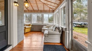 Une pièce chaleureuse avec un plafond en bois, de grandes fenêtres et un canapé.