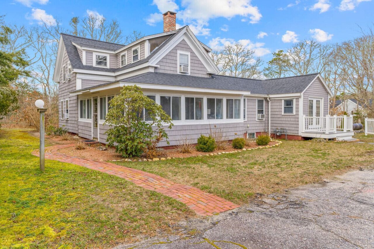A two-story house with a large front porch, a chimney, and a well-maintained lawn.