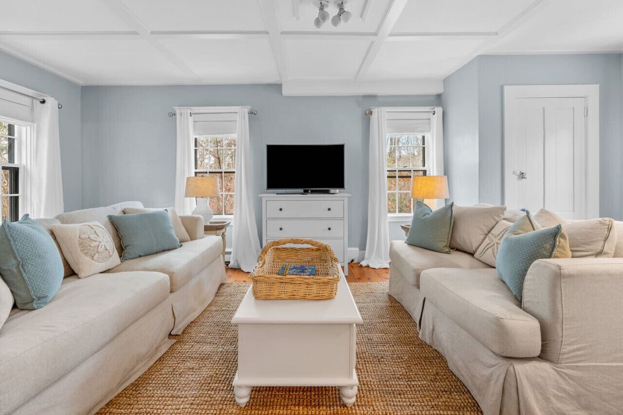 A living room with two beige sofas, a white coffee table, a flat-screen TV, and a wicker basket.