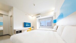 A modern hotel room with a large bed, a flat-screen TV, a desk, and a window with a city view.