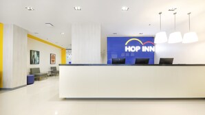 A hotel reception area with a reception desk, seating area, and a large blue sign with the hotel name.