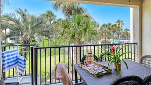 A balcony with a view of palm trees and a pool. - Beach Views, 2 Balconies, Beach Access, 2 Pools 1 Heated, 5 miles to Downtown, $300 in Free Tickets! (St. Augustine)