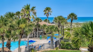 A pool area with palm trees, a fenced deck, and a view of the ocean. - Beach Views, 2 Balconies, Beach Access, 2 Pools 1 Heated, 5 miles to Downtown, $300 in Free Tickets! (St. Augustine)