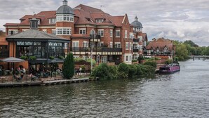 Un bâtiment situé au bord de la rivière, avec un café et un bateau amarré à proximité.
