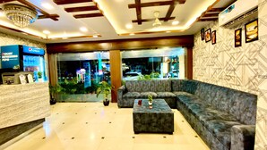 A lobby with a reception desk, seating area, and a large window with a view of the street. - Hotel Sky Park - Airport Zone (Hyderabad)