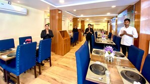 Un restaurante con sillas tapizadas en azul, mesas de madera y una decoración interior moderna.