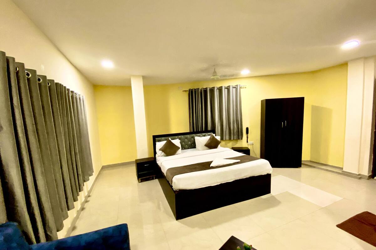 Una habitación de hotel con una cama grande, una mesita de noche, un armario y una silla azul.