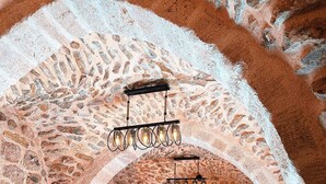 An interior with stone walls, wooden tables, and chairs, and hanging light fixtures. - Marvel Otel (Mardin)