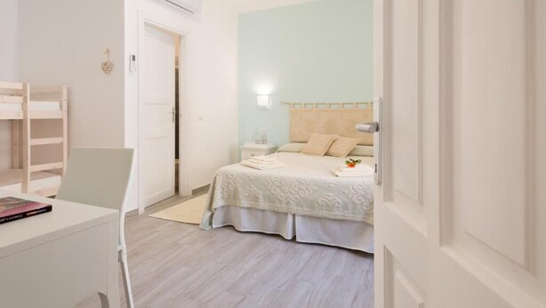 Un dormitorio con cama, mesita de noche y escritorio con silla.