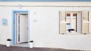 Un edificio con fachada blanca, marco de puerta azul y ventana con persianas.