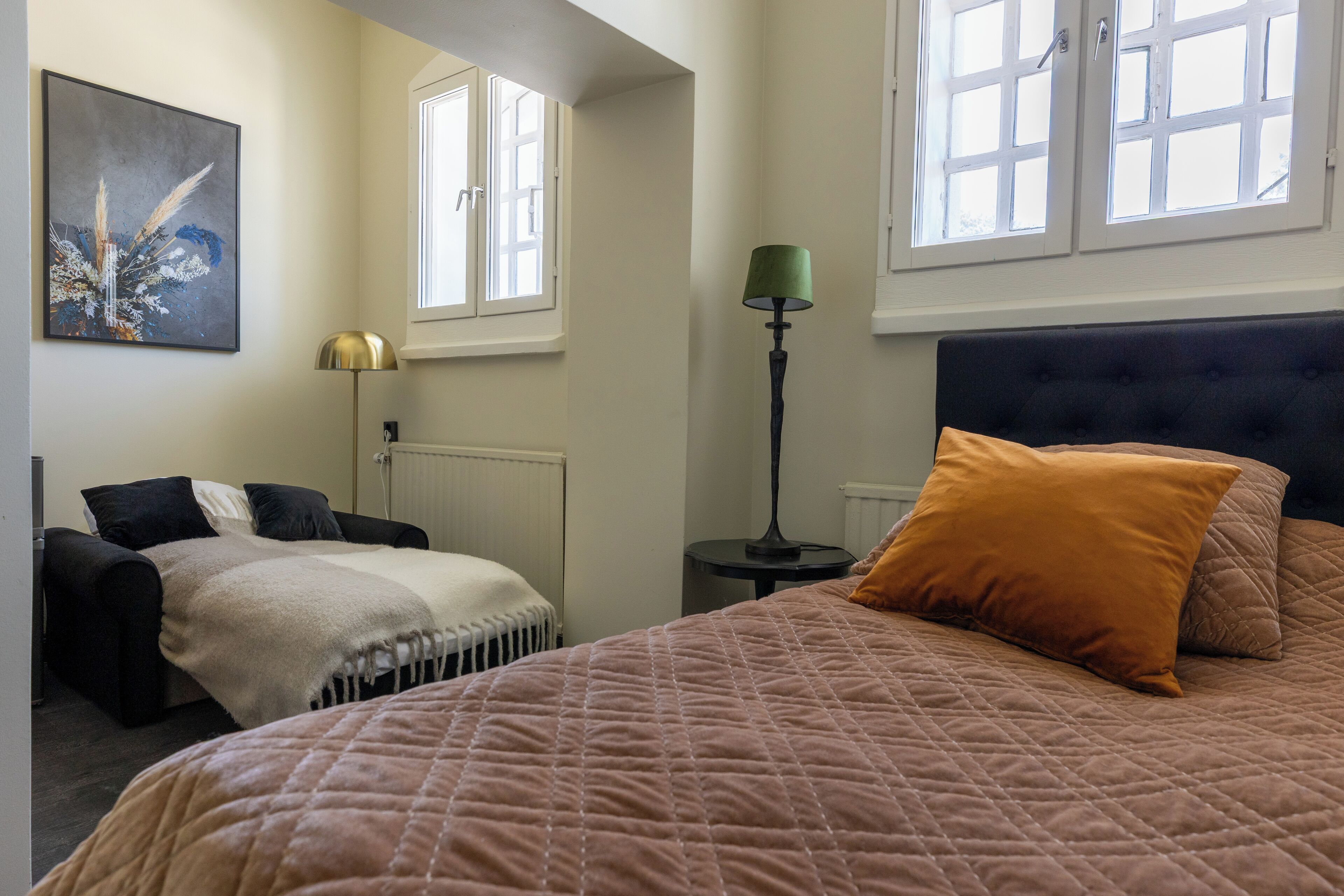 A bedroom with a large bed, a bedside table, a lamp, and a window.